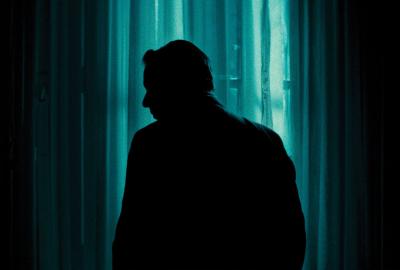 The stark silhouette of a man, his back to you, gazing out at something unseen beyond the frame.